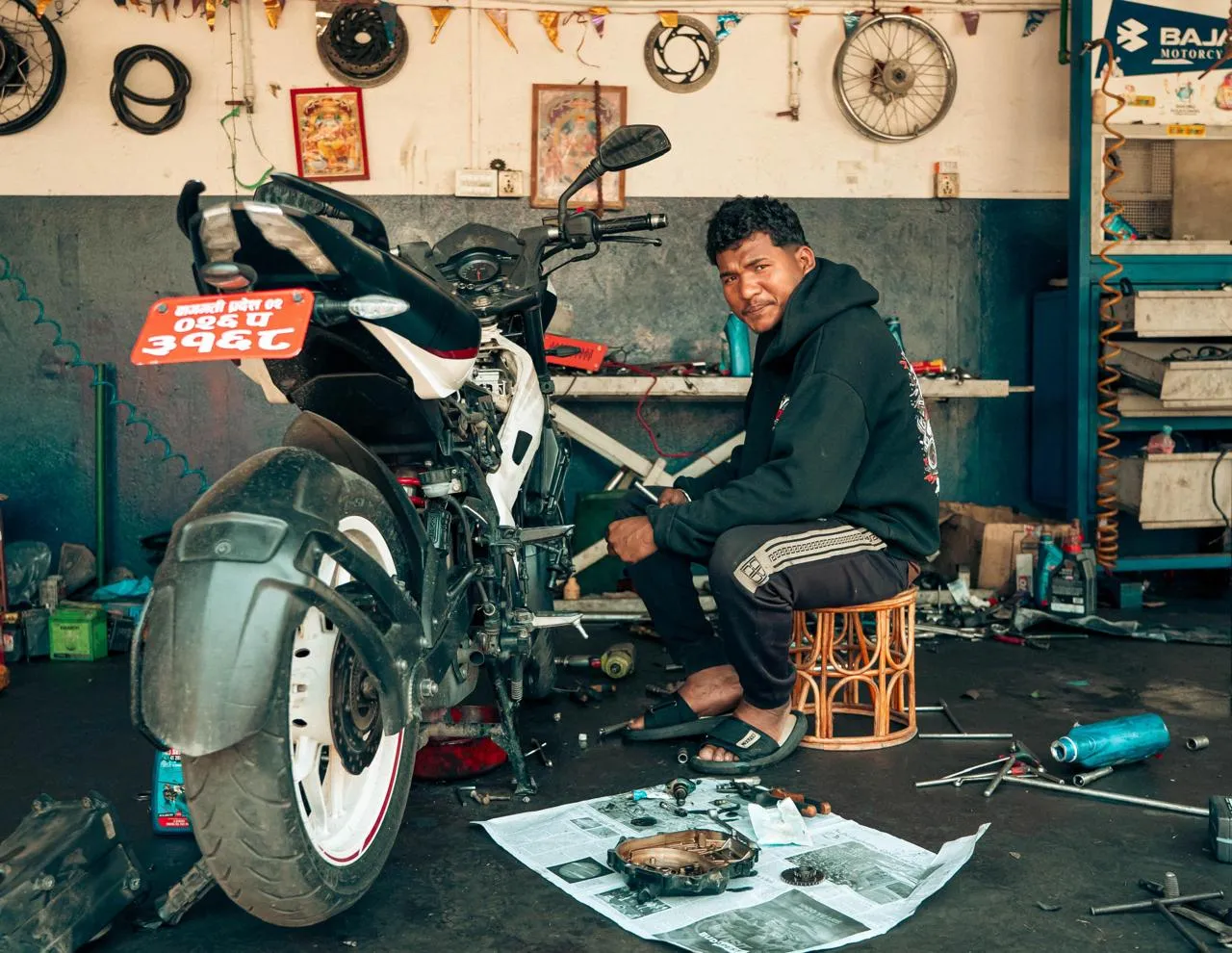 Rev and Ride mechanic beside a stripped-down motorcycle in the Kapan workshop